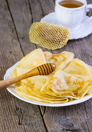 pancakes with honey on a white plate on a wooden backgroundの写真素材