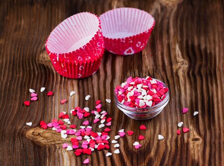 confectionery hearts and baking dishes on a wooden backgroundの写真素材