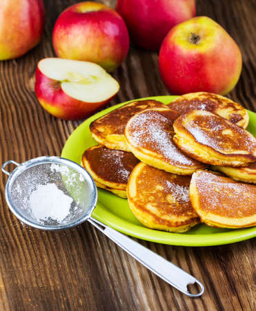 pancakes with apples on a green plate on a wooden backgroundの写真素材