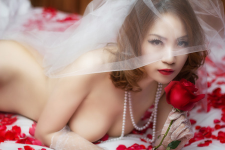 The sexy Asian woman lies in petals of roses の写真素材