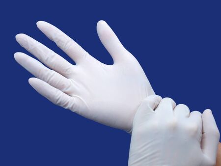 two hands wearing nitrile glove over blue background 