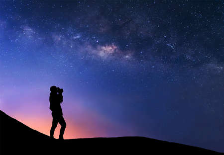 Silhouette of woman is taking the milky way photo on top of mountain before sunsire.の写真素材