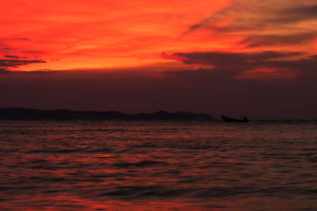 A small fishing boat in the sea on cloudy day and colorful sunset sky.の写真素材