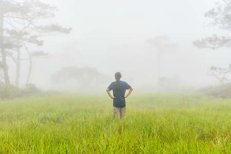 Happy young woman stand and akimbo in misty day on green meadow.の写真素材