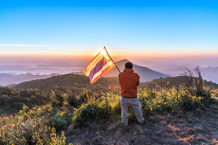 Young man standing on top of mountain and enjoy sunset view.の写真素材
