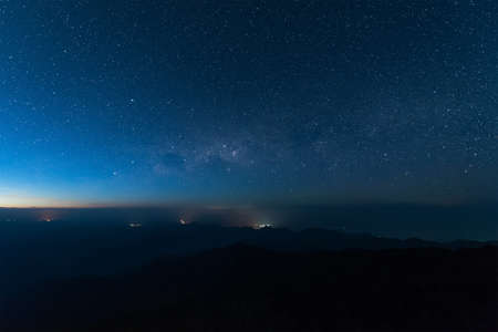 Stars illuminated above the dark silhouette mountain before sunrise.