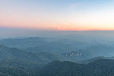 Fog covered forest and mountain at sunset.の写真素材