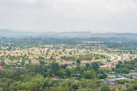 Curve road, Village and town surrounded by countryside with mountain background in central of Thailand.の写真素材