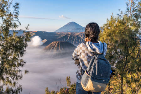A tourist woman enjoying to fog covered Bromo mountain valley at sunrise.の写真素材
