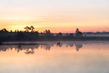 Morning sunrise over the lake with silhouette tree reflect on water surface at Phu Kradaung, national park in Thailand.の写真素材