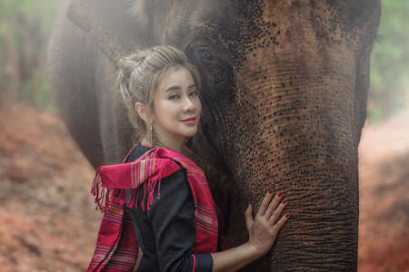 Beautiful Asian Woman wears thai dress with her elephant. Closeup portrait of a beautiful girl with elephant.の写真素材