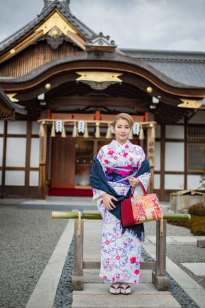 Woman dressed in traditional japanese costume walking under tori gates at the fushimi-inari shrine, Kyoto Japanの写真素材