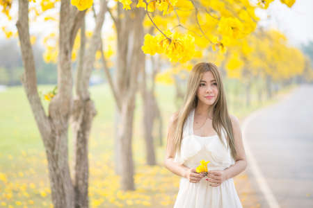 portrait of a beautiful young sexy girl brunette bride with flowers in her hair look attractive in a white dress on a background of autumn forest and leaves posing and smiling at chiangmai thailandの写真素材
