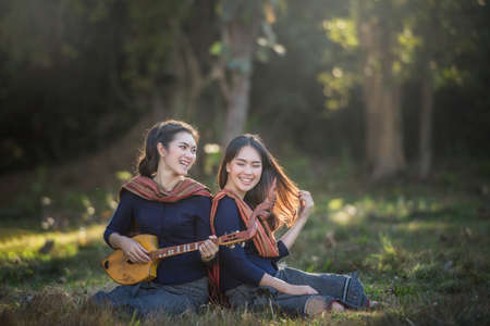 Happy asian woman in traditional, she sing a song and play pin (Thai akulele)の写真素材