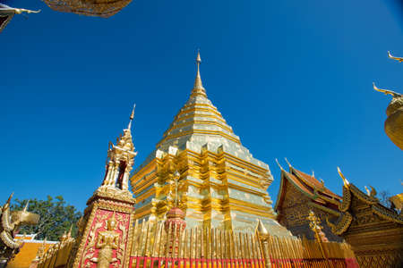Gold pagoda and gold buddha statue with blue sky at Wat Phra That Doi Suthep, Chiang Mai, Thailand.の写真素材