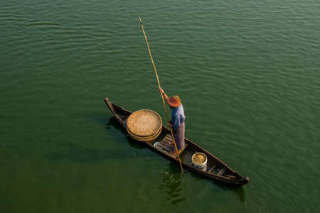 Unidentified people fish in a lake in Amarapura, Myanmar. Amarapura is famed for the longest teak...