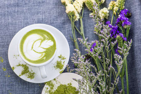 reen tea / Matcha latte in a cup with matcha powder on the wooden table