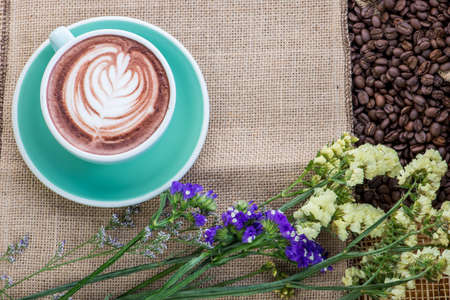 Cup of coffee on coffee beans background on a wooden tableの写真素材