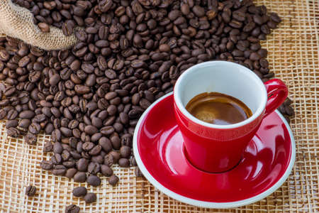 Cup of coffee on coffee beans background on a wooden tableの写真素材