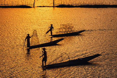 Intha Burmese fishermen on boat catching fish traditional at Inle Lake, Shan State, Myanmarの写真素材