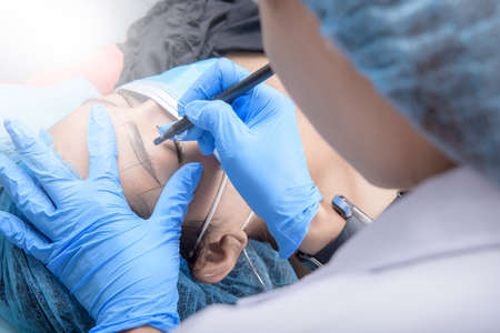 Microblading eyebrows workflow. Permanent makeup for Eyebrows having professional eyebrow tattoo in...