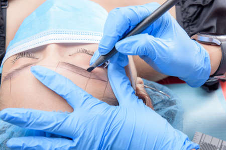 Microblading eyebrows workflow. Permanent makeup for Eyebrows having professional eyebrow tattoo in beauty salon.の写真素材