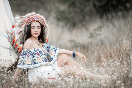 Boho bohemian girl styled wearing Indian maxi dress and jewellery in autumn fieldの写真素材
