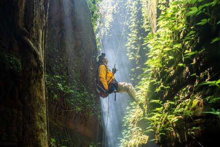 Rescue hiker with backpack climbs natural rocky wall. Wearing in climbing equipment rope carabinerの写真素材