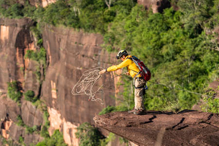 Rescue hiker with backpack climbs natural rocky wall. Wearing in climbing equipment rope carabiner