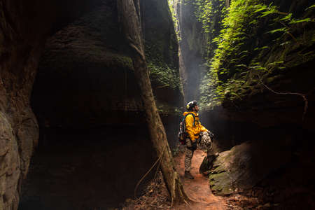 Rescue hiker with backpack climbs natural rocky wall. Wearing in climbing equipment rope carabiner