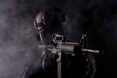 Spec ops police officer SWAT special forces  with a weapon in his hands. on a dark background. Law...