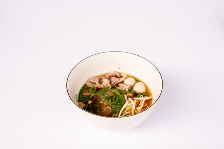 Noodles with pork and pork balls with soup Thai style in white bowl