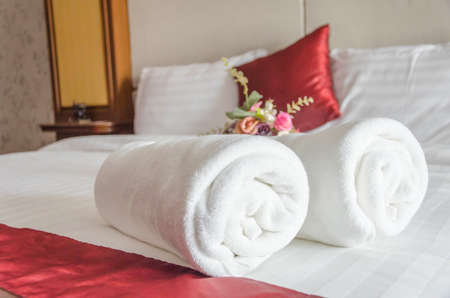 White towel on clean bed,background blured red and white pillows,  summer holiday and vacation concept,selective focus.の写真素材