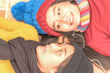 Close up of  two teenage girls wear colorful clothes,laying down on floor and smile,winter concept,copy space.の写真素材