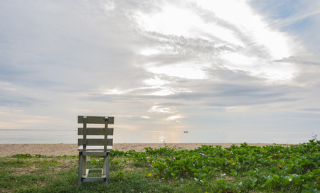 old wooden white chair on beach at sunrise timeの写真素材