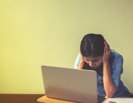 Portrait of a young business woman using laptop and hold her head wth stressの写真素材