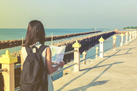 traveler girl looking at the sea with map, travel and active lifestyle conceptの写真素材