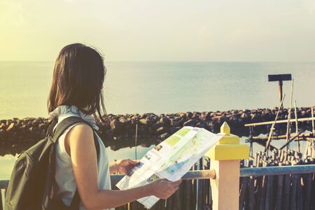 traveler girl looking at the sea with map, travel and active lifestyle conceptの写真素材