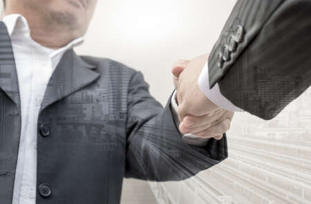 Businessmen shaking hands making an agreement, Double exposure of handshake and cityの写真素材