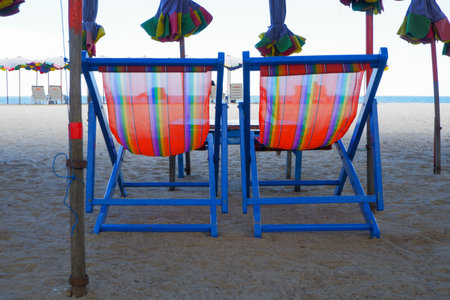 Chairs to sit and lie on the beach and a large umbrella located on the sandy beach by the sea.の写真素材