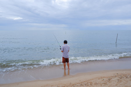 man standing fishing by the sea.On a relaxing dayの写真素材