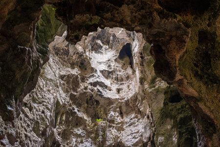 Low angle view of a dark cave exit with sunlight streaming into the cave shaft.の写真素材