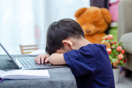 Asian boy sleeping while studying online on laptop