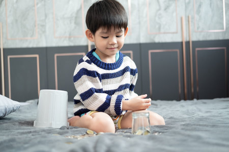 Asian boy happily counting coins to save moneyの写真素材
