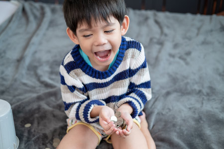 Asian boy happily counting coins to save moneyの写真素材