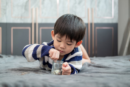 Asian boy happily counting coins to save moneyの写真素材