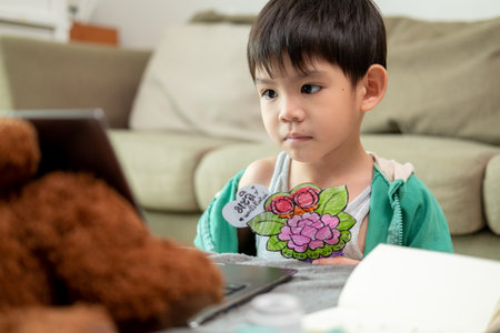 Asian boy studying online and doing activities on laptop