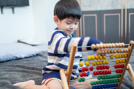Asian boy playing with toys on the bedの写真素材