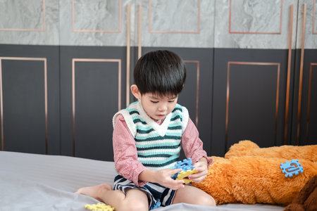 Asian boy playing with jigsaw puzzles on the bed joyfullyの写真素材