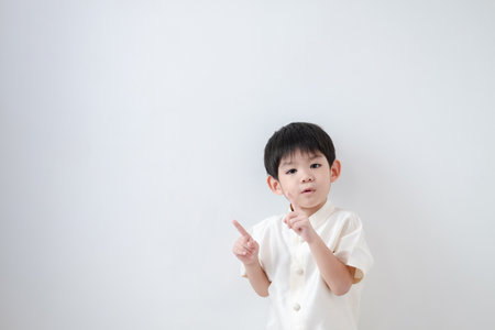 Asian boy Wearing traditional Thai clothing, standing with index finger upwards. on a white backgroundの写真素材
